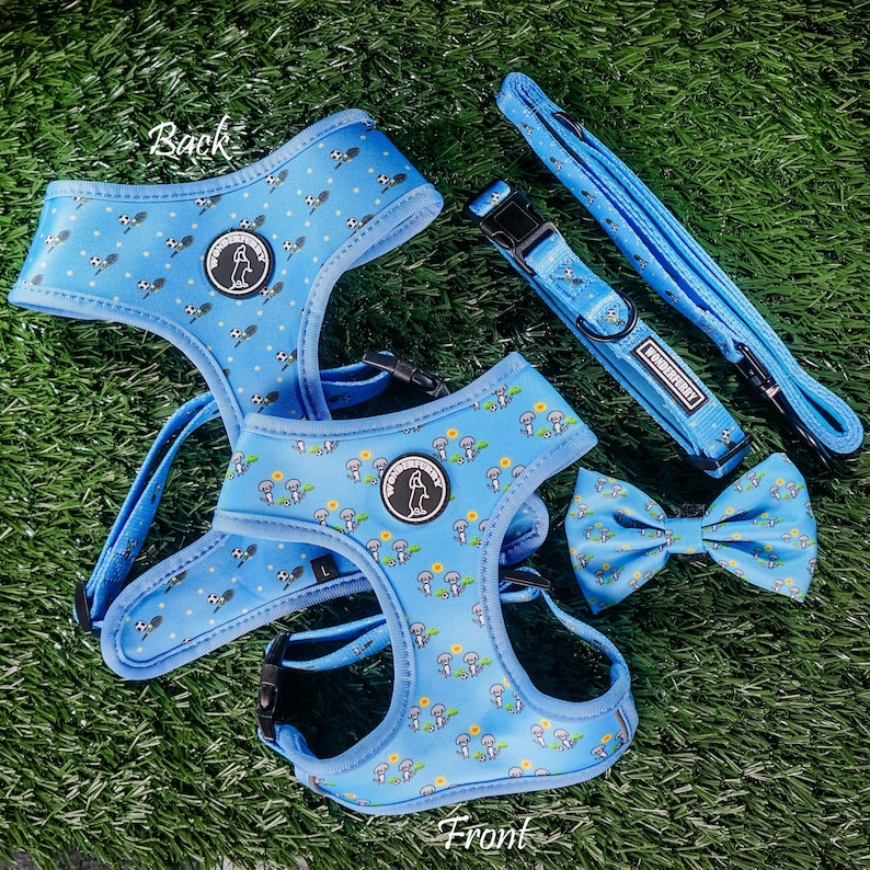 May include: A light blue dog harness, collar, leash, and bow tie set. The set features a repeating pattern of small white and black dog illustrations and a mushroom design. The collar and harness have the brand name "WONDERFURRY".