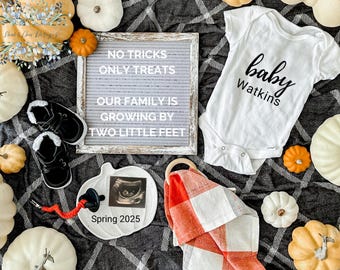 May include: A white onesie with the text "baby Watkins" in black lettering, a letter board with the text "No tricks only treats our family is growing by two little feet", a white pumpkin with a black and white ultrasound image, a red and white checkered blanket, and a pair of baby shoes.