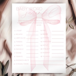 May include: A pink and white baby shower game with a pink bow on top. The game is called "Baby Word Scramble" and asks players to unscramble the words below. Whoever has the most correct answers when the time is up wins.
