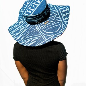 May include: A wide-brimmed sun hat with a blue and white geometric pattern. The hat has a round crown and a wide brim that extends out to the sides. The hat is made of a lightweight fabric and has a comfortable fit.