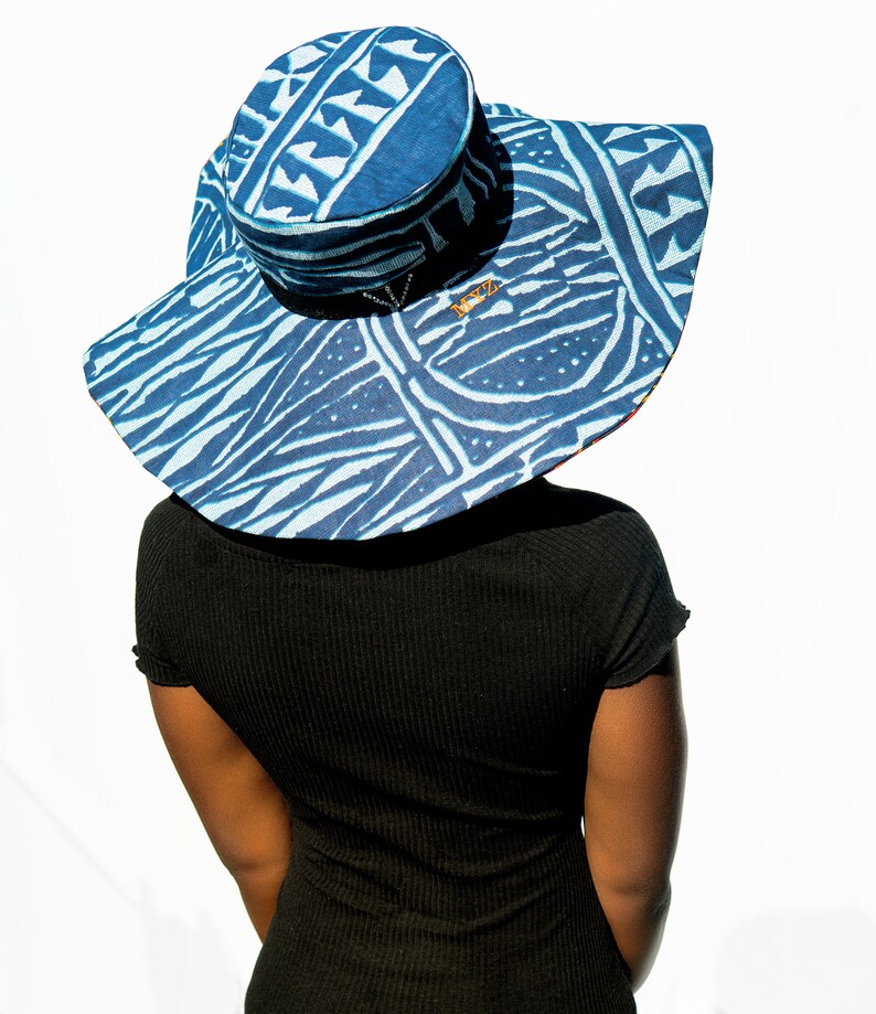 May include: A wide-brimmed sun hat with a blue and white geometric pattern. The hat has a round crown and a wide brim that extends out to the sides. The hat is made of a lightweight fabric and has a comfortable fit.