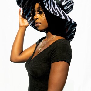 May include: A black and white zebra patterned sun hat with a wide brim. The hat has a black ribbon around the crown.