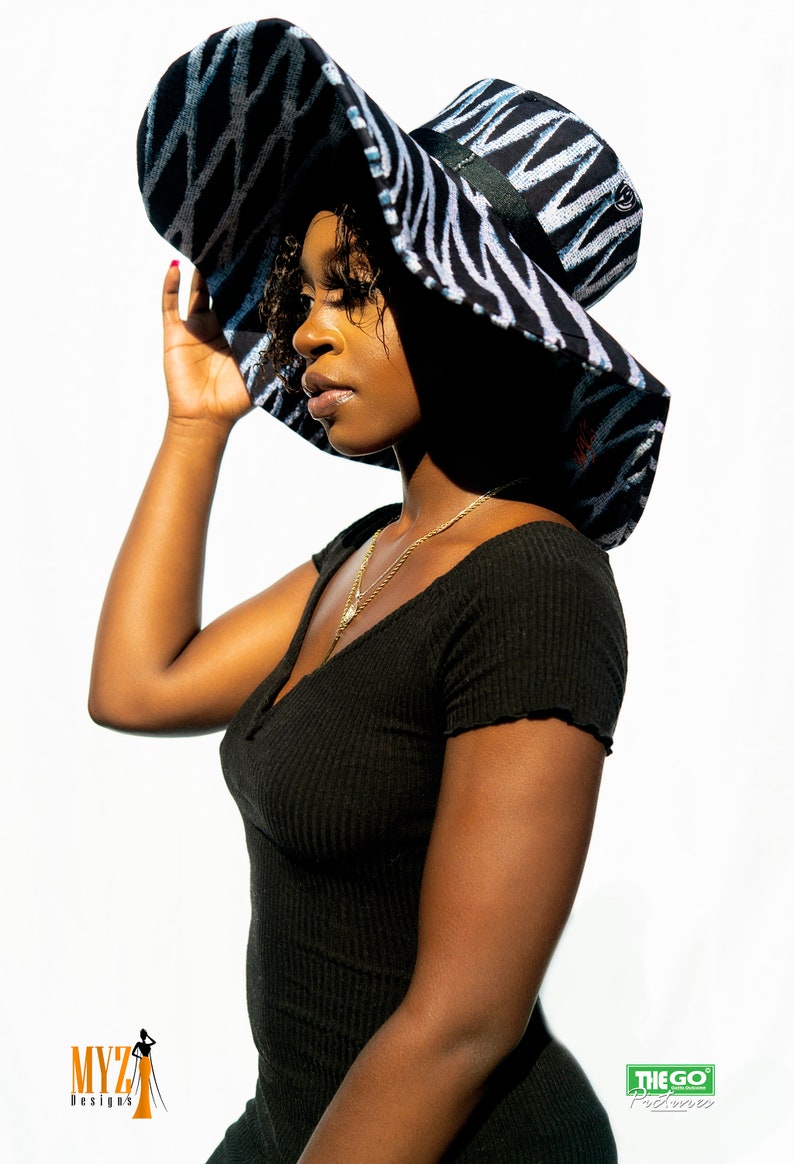 May include: A black and white zebra patterned sun hat with a wide brim. The hat has a black ribbon around the crown.