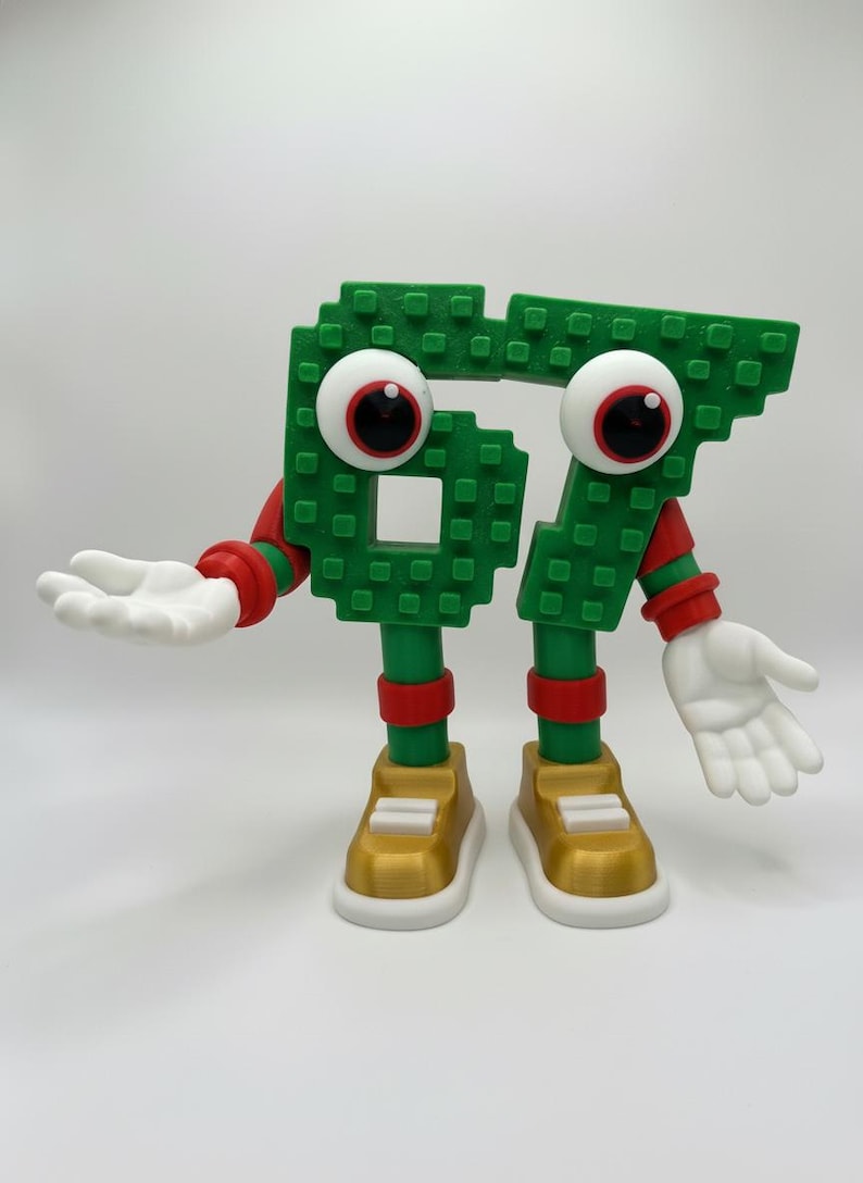May include: A whimsical green number 67 figure with large googly eyes, red accents, and white hands. The figure is wearing gold and white sneakers. The number is made of small square blocks.