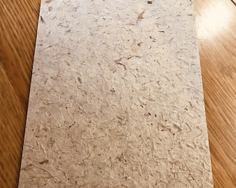 May include: A sheet of textured, off-white paper with a natural fiber look. The paper has a rough, uneven surface with visible fibers throughout.