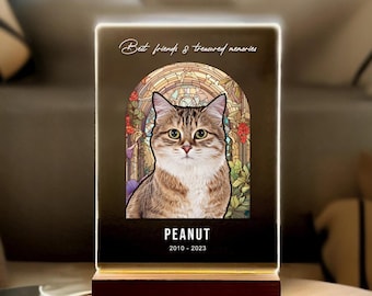 May include: A memorial light with a stained glass design featuring a cat. The text "Best friends & treasured memories" is at the top, and the cat's name "Peanut" and the dates "2010 - 2023" are at the bottom.