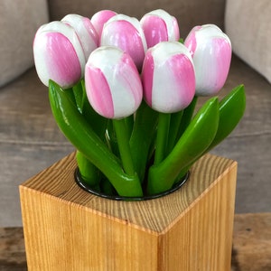 May include: A square wooden vase with a light brown finish. The vase is filled with a bouquet of pink and white wooden tulips.
