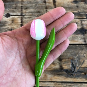 May include: A wooden tulip with a white and pink painted flower and a green stem.
