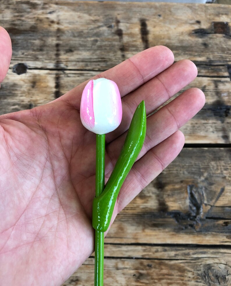 May include: A wooden tulip with a white and pink painted flower and a green stem.