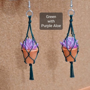 Puede incluir: Un par de pendientes de macram&eacute; verde con una planta suculenta morada en una maceta peque&ntilde;a de terracota. Los pendientes est&aacute;n etiquetados como "Verde con Aloe morado".