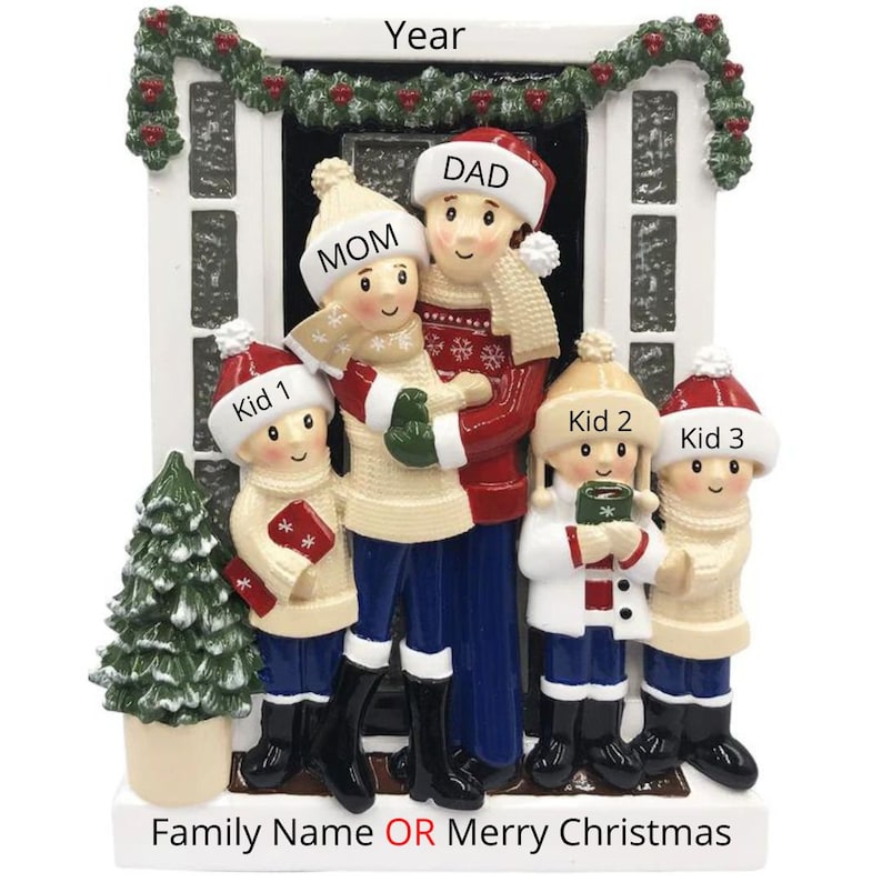 May include: A white and red Christmas ornament depicting a family of five standing in front of a house. The family is wearing winter clothes and hats. The text "Year" is at the top of the ornament. The text "Family Name OR Merry Christmas" is at the bottom of the ornament.