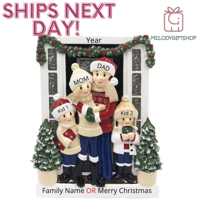 May include: A white ceramic Christmas ornament depicting a family of four standing in front of a house. The family is dressed in winter clothing and the house is decorated with a wreath and garland. The ornament is personalized with the names "Mom", "Dad", "Kid 1", and "Kid 2". The text "Year" is also included on the ornament. The ornament is a great way to commemorate a special family Christmas.