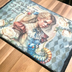 May include: A rectangular slate serving board with an Alice in Wonderland illustration. The artwork shows Alice, a caterpillar, and roses, with the quote: "If you don't know where you are going any road can take you there."