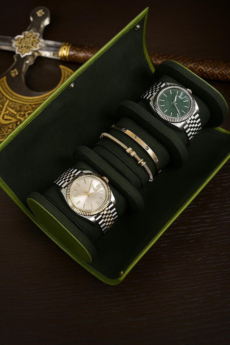 May include: A green watch case containing two silver and gold watches and two gold bracelets. The watches have silver and gold straps and light-coloured faces. The bracelets are gold with small decorative features. The case has a green trim.
