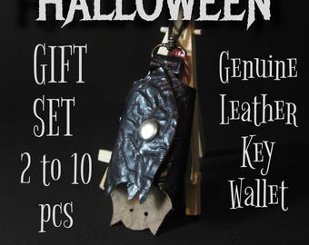 May include: A black leather key wallet with a bat-wing design, featuring a silver button and a metal clasp. The image includes the text "HALLOWEEN GIFT SET" and "Genuine Leather Key Wallet."