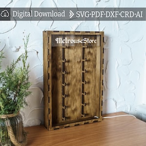 Puede incluir: Una vitrina de pared de madera con un frente de acrílico transparente. La vitrina tiene un acabado de tinte marrón y presenta múltiples ranuras para guardar artículos. El texto "MelrouseStore" está impreso en la parte frontal de la vitrina.