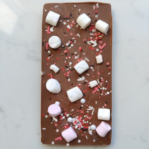 May include: A chocolate bar with white and pink marshmallows and red and brown sprinkles.