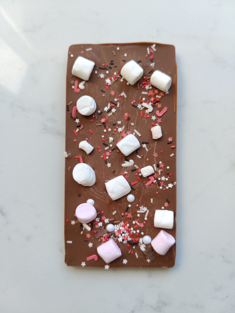 May include: A chocolate bar with white and pink marshmallows and red and brown sprinkles.
