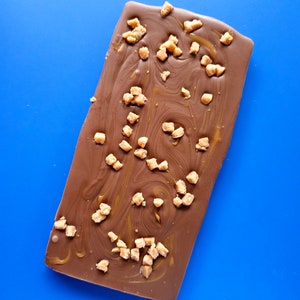 May include: A chocolate bar with a swirl of caramel and pieces of toffee on top.