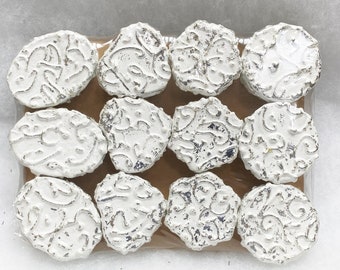 May include: A set of 10 white ceramic tiles with a silver metallic glaze and a decorative floral pattern. The tiles are packaged in a clear plastic bag.