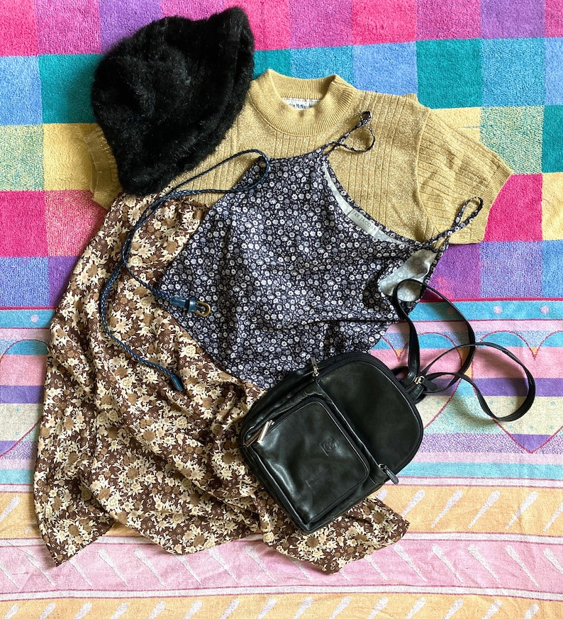 May include: A brown and beige floral print skirt, a black and white floral print dress, a black leather backpack, a black fur hat, and a beige sweater with a brown knit texture.