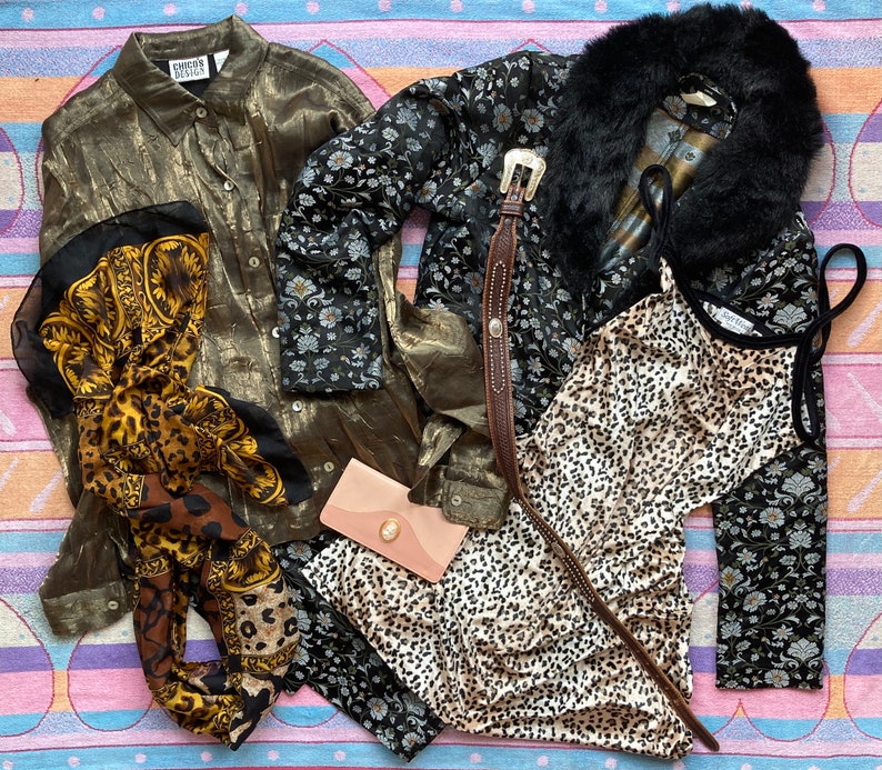 May include: A collection of vintage clothing items including a gold silk blouse, a black and white floral print blouse, a leopard print top, and a black fur collar.