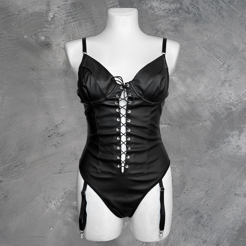 May include: Black leather bodysuit with a lace-up front and adjustable straps. The bodysuit has a garter belt with straps.