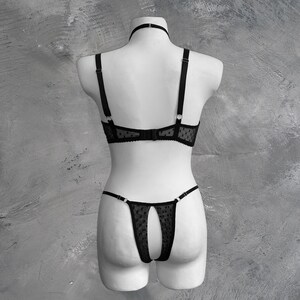May include: Black lingerie set with a polka dot pattern. The bra has adjustable straps and a delicate lace trim. The matching panty has a cutout design in the back.