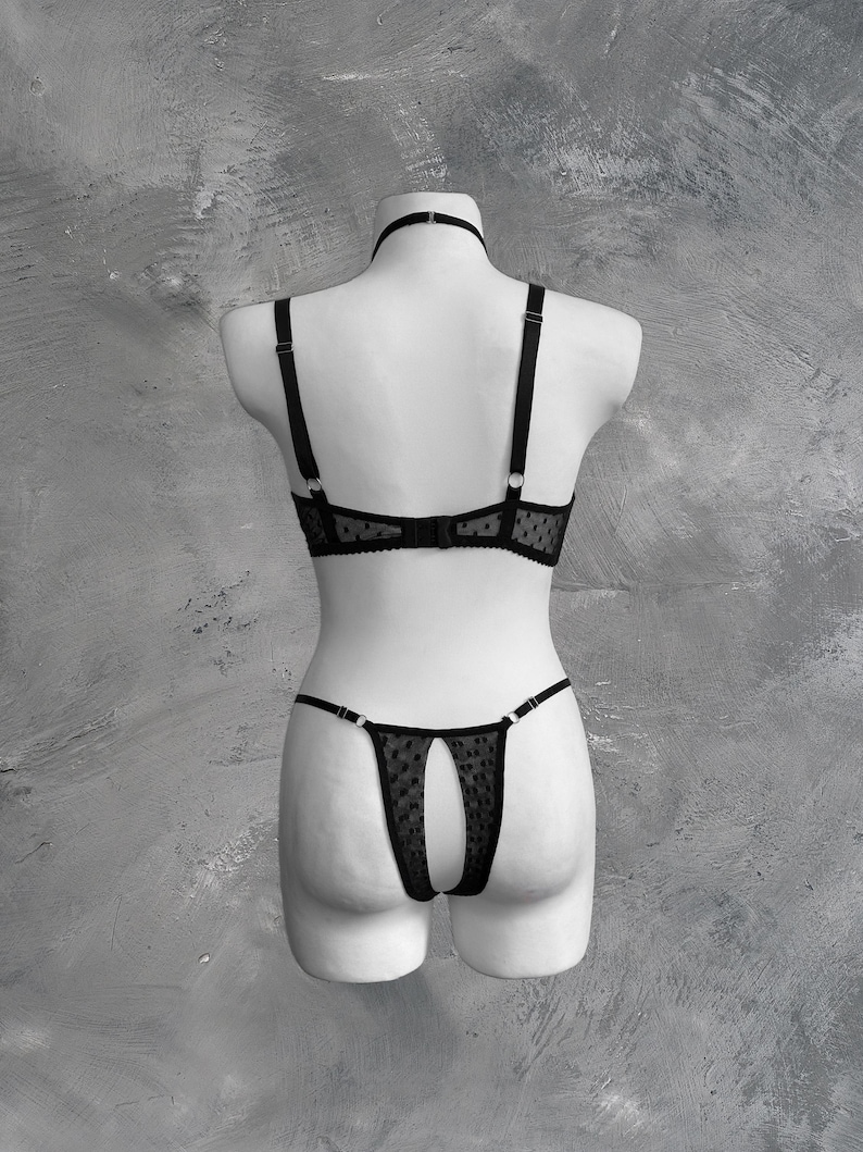 May include: Black lingerie set with a polka dot pattern. The bra has adjustable straps and a delicate lace trim. The matching panty has a cutout design in the back.