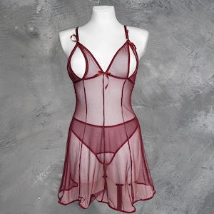 May include: A burgundy sheer lingerie dress with a V-neckline and thin straps. The dress has a scalloped hem and a delicate bow at the center of the neckline.