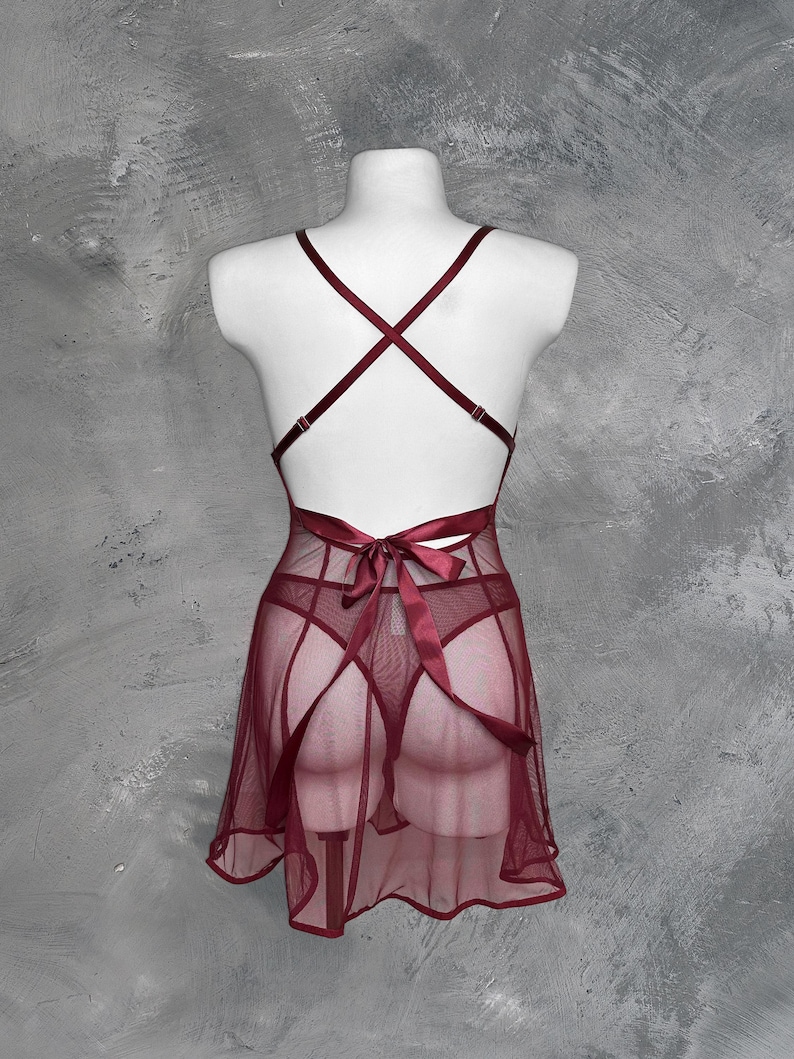 May include: A burgundy mesh slip dress with a satin ribbon tie at the back.