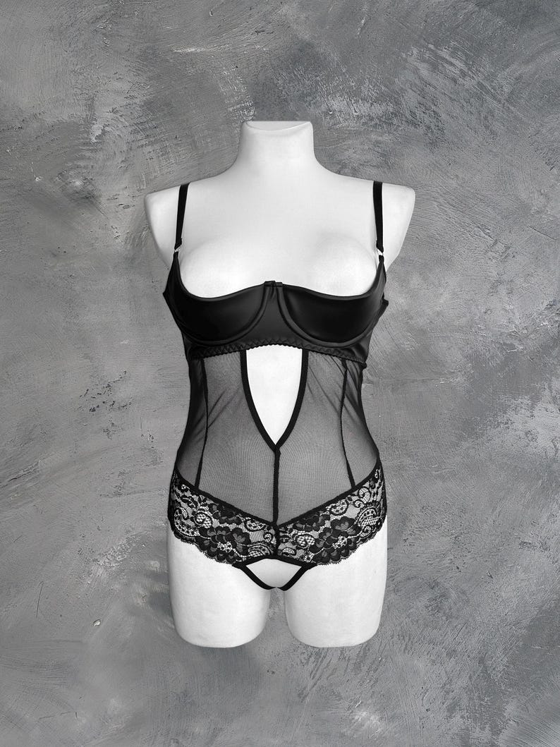 May include: Black lingerie with a lace bottom and a satin top. The top has a plunging neckline and adjustable straps.