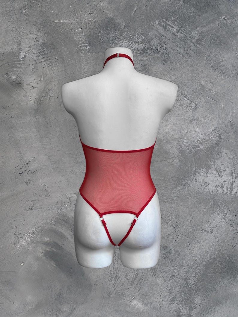 May include: Red mesh bodysuit with a halter neck and adjustable straps. The bodysuit has a low back and a thong style bottom.