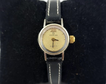 Vintage Omega De Ville Quartz watch with a black leather strap and a gold-colored face