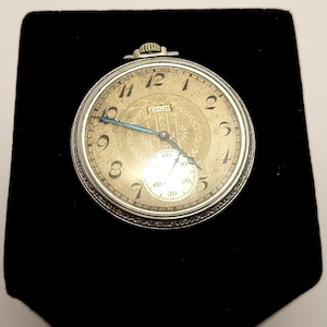 Vintage Elgin 315 pocket watch. Silver toned case with crystal back showing movement.