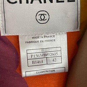 May include: Close-up of a label with the word "CHANEL" in black capital letters. Below the text is the Chanel logo, a pair of interlocking Cs. The label also includes text that reads "MADE IN FRANCE" and other product information.