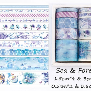 May include: A set of 10 washi tapes with blue and purple watercolor designs. The tapes feature various patterns, including flowers, fish, hexagons, and stripes. The set includes four 1.5-inch tapes, two 3-inch tapes, two 0.5-inch tapes, and two 0.8-inch tapes. The tapes are packaged in a clear plastic box with the text "Sea & Forest" printed on the front.