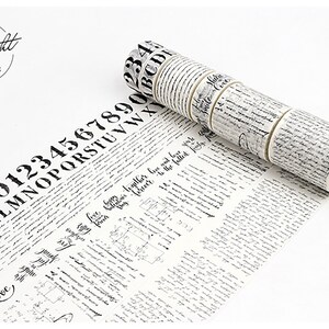 May include: A set of black and white patterned washi tape rolls with various designs, including numbers, letters, and cursive writing. The tape is unrolled and shows the designs.