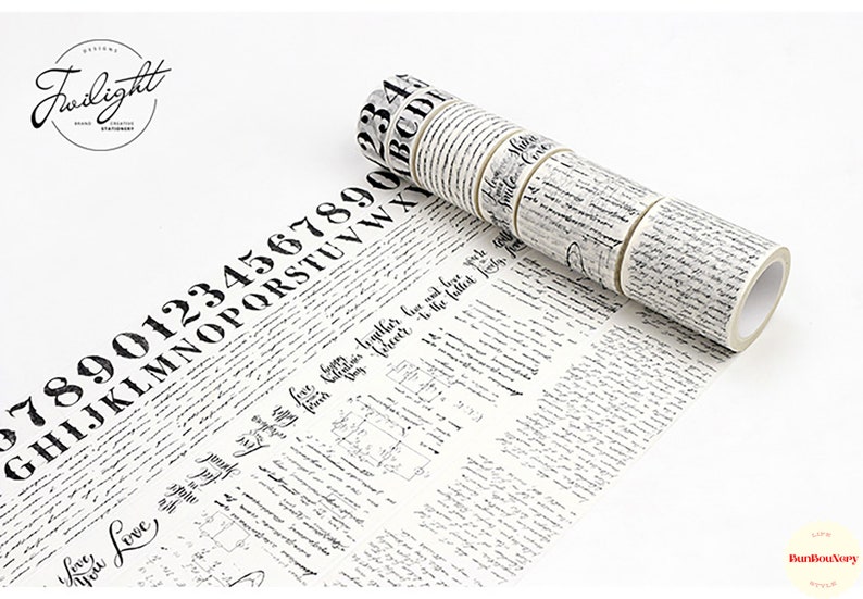 May include: A set of black and white patterned washi tape rolls with various designs, including numbers, letters, and cursive writing. The tape is unrolled and shows the designs.