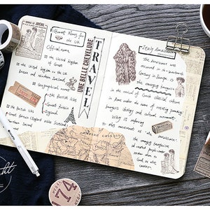 May include: A close-up of a notebook with a variety of decorative washi tapes, including a map, a vintage newspaper, and a floral design. The notebook is open to a page with handwritten notes about travel and history. The notebook is on a wooden surface with a cup of coffee and a pair of scissors.