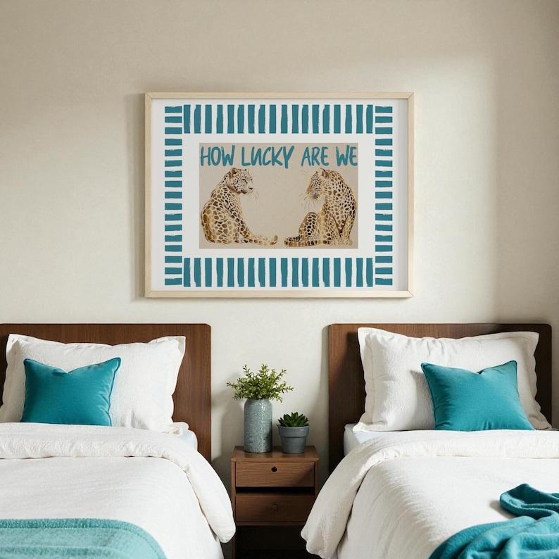 K&ouml;nnte beinhalten: Ein gerahmtes Kunstwerk mit zwei Leopardenillustrationen und dem Text "HOW LUCKY ARE WE" in T&uuml;rkis. Das Kunstwerk hat einen t&uuml;rkisfarbenen Streifenrand. Das Bild befindet sich &uuml;ber zwei Betten mit t&uuml;rkisfarbenen Kissen.