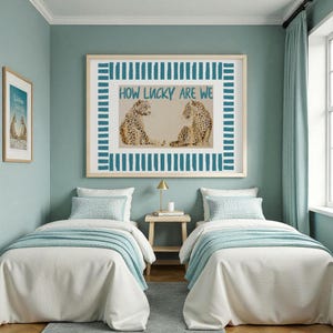 K&ouml;nnte beinhalten: Ein Schlafzimmer mit zwei Einzelbetten, jeweils mit wei&szlig;er Bettw&auml;sche und hellblauen Decken. &Uuml;ber den Betten h&auml;ngt ein gerahmtes Kunstwerk mit zwei Leoparden und dem Text "HOW LUCKY ARE WE". Die W&auml;nde sind in einem sanften T&uuml;rkis gestrichen.