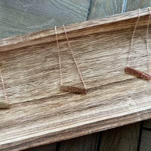 May include: Three gold necklaces with a bar pendant. Each bar pendant has a different design.