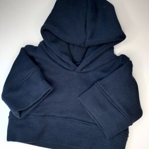 Könnte beinhalten: Ein dunkelblauer Kapuzenpullover mit langen Ärmeln und geripptem Saum.