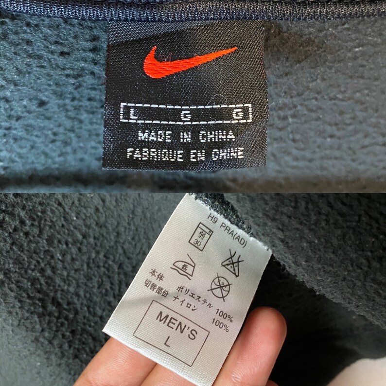 May include: Black Nike sweatshirt with a white tag that says "Made in China" and "Fabrique en Chine". The tag also has a size L and a Nike swoosh logo. The sweatshirt has a white tag with washing instructions and a size L.
