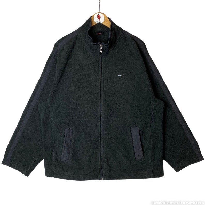 May include: Black fleece zip-up jacket with a silver Nike swoosh logo on the left chest and black stripes down the sleeves.