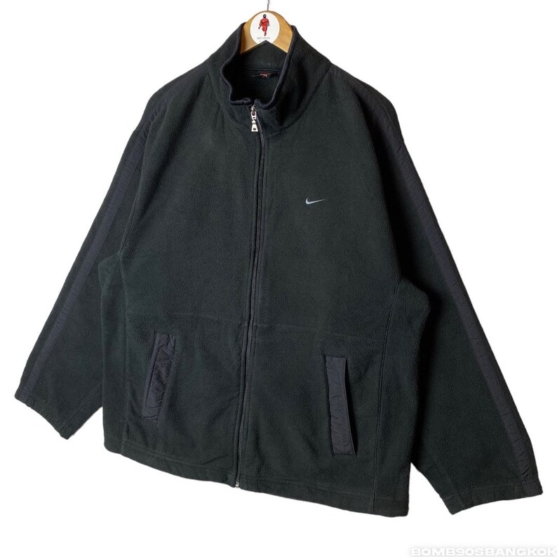 May include: Black fleece zip-up jacket with a Nike logo on the left chest. The jacket has a high collar and two pockets.