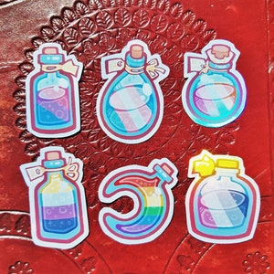 Peut inclure: Six autocollants colorés représentant différentes fioles de potion avec différents motifs. Les autocollants sont sur un fond en cuir rouge.