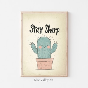 Puede incluir: Una impresión de arte imprimible beige con un cactus de dibujos animados en una maceta rosa. El cactus es verde y tiene una cara sonriente. El texto "Stay Sharp" está escrito en negro sobre el cactus.