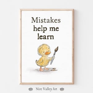 May include: A framed print featuring the words "Mistakes help me learn." The image shows a yellow duckling holding a paintbrush. The artwork is in a light wood frame, suitable for a child's room or nursery.